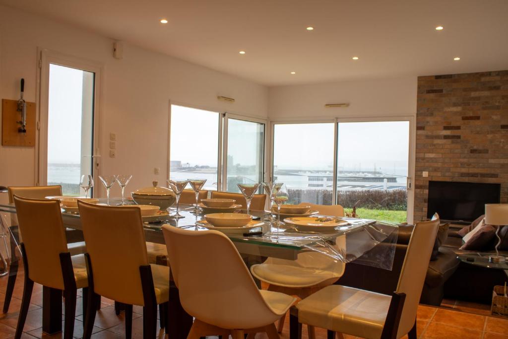 a dining room with a table and chairs and windows at Ti Ma Zud/Vue mer/Wifi in Camaret-sur-Mer