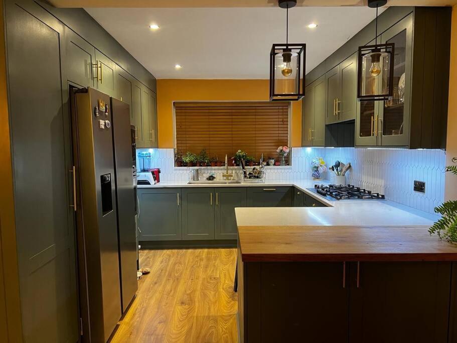 a large kitchen with green cabinets and a counter at Charming Family Home with Gym in Henley on Thames