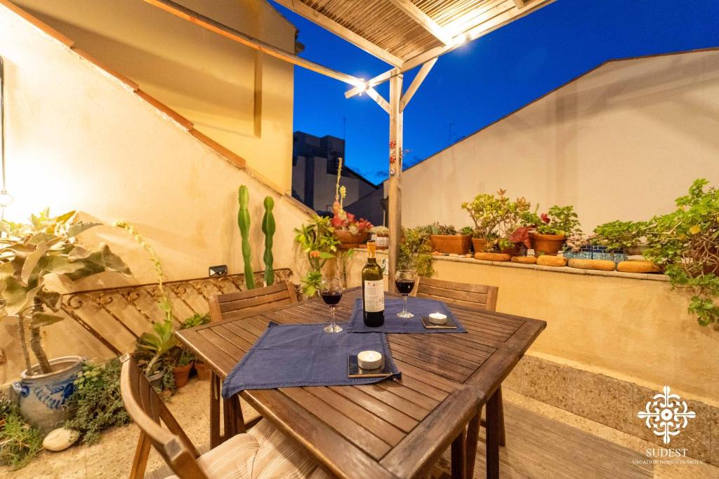 a wooden table and chairs on a patio with plants at Casa Sophia in Siracusa