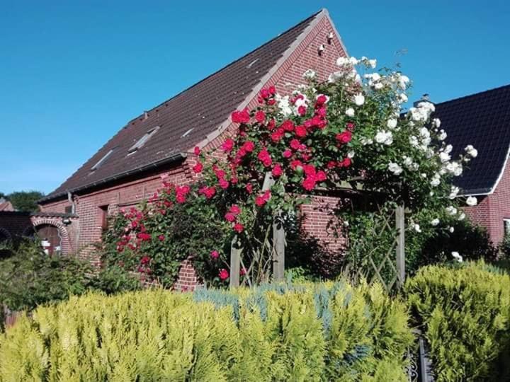a red brick building with red and white flowers on it at Ferienwohnung Casa Capurso in Glückstadt
