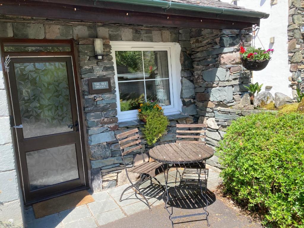 a table and chairs next to a building with a window at The Old Smithy, Ullswater in Glenridding