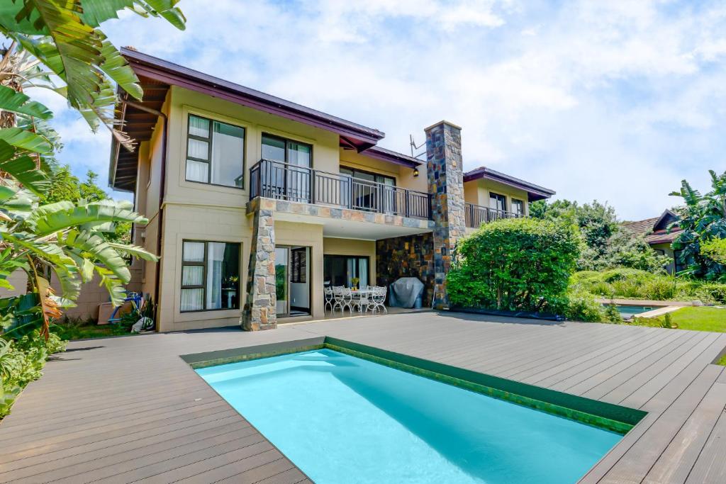 a house with a swimming pool in front of a house at Baluwatu 10, Zimbali Estate in Ballito