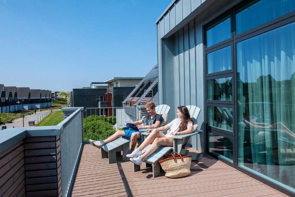 two people sitting on the balcony of a building at Strandhaus-Shell in Hörnum