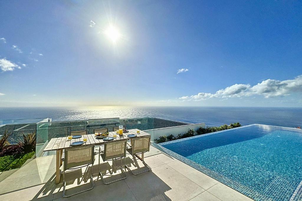 a dining table and chairs next to a swimming pool at Villa OceanAIR by LovelyStay in Prazeres