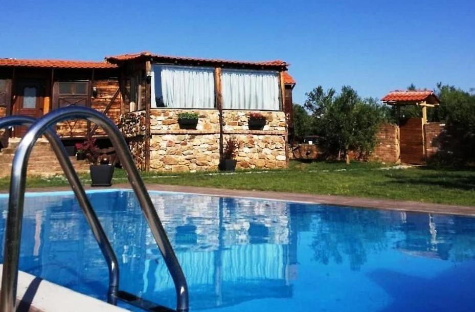 a swimming pool in front of a stone house at LOS VAGONES 1 in Vatopedi