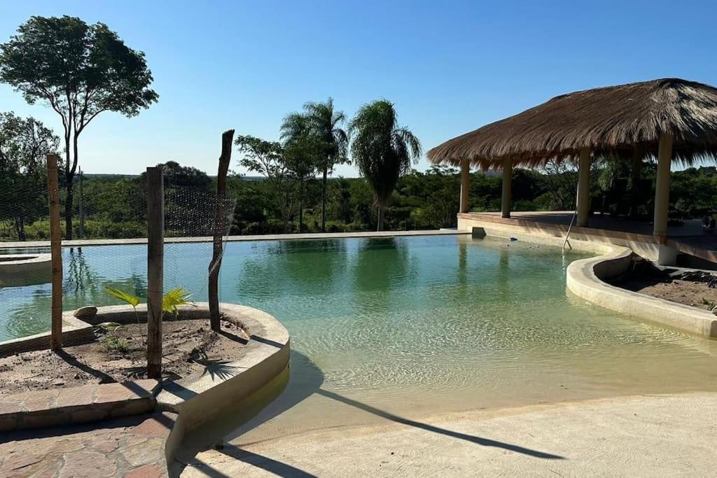 een zwembad met een rieten parasol en een resort bij Luxux Ferienwohnung Indepedencia Casa Blanca No.3 in Independencia