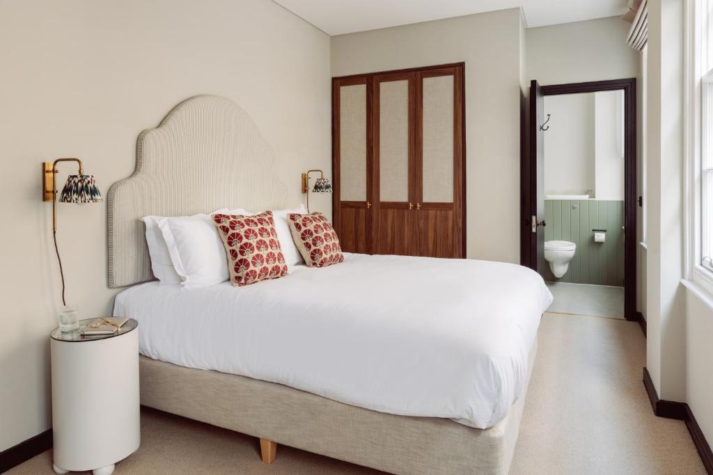 1 dormitorio con 1 cama blanca grande con almohadas rojas en Native Kings Wardrobe, en Londres
