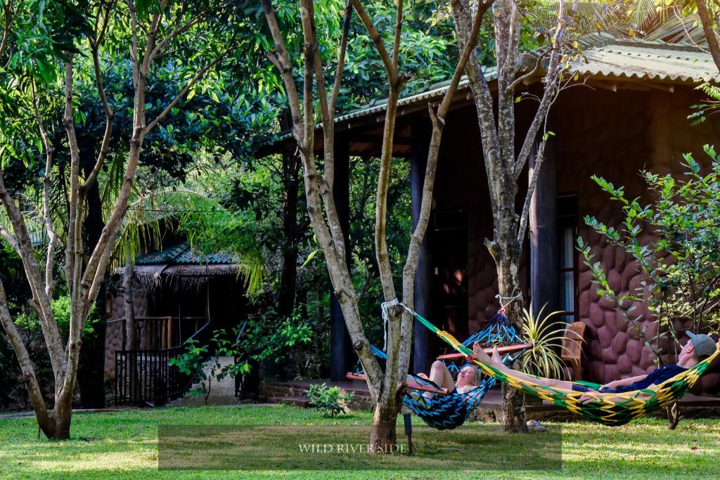 a person laying in a hammock in front of a house at Wild River Side in Udawalawe