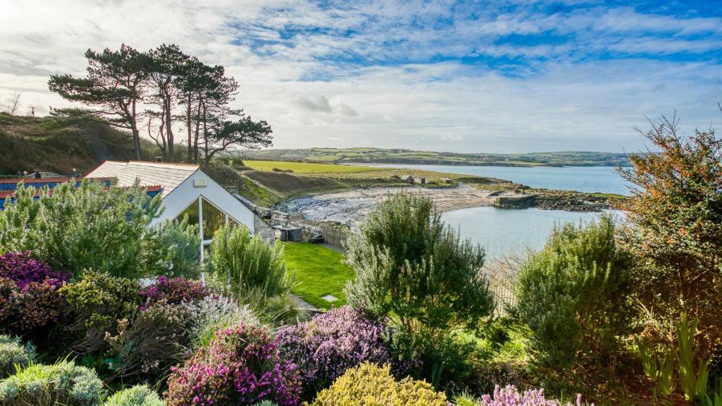 a view of a garden with flowers and a lake at Moryn in Moelfre