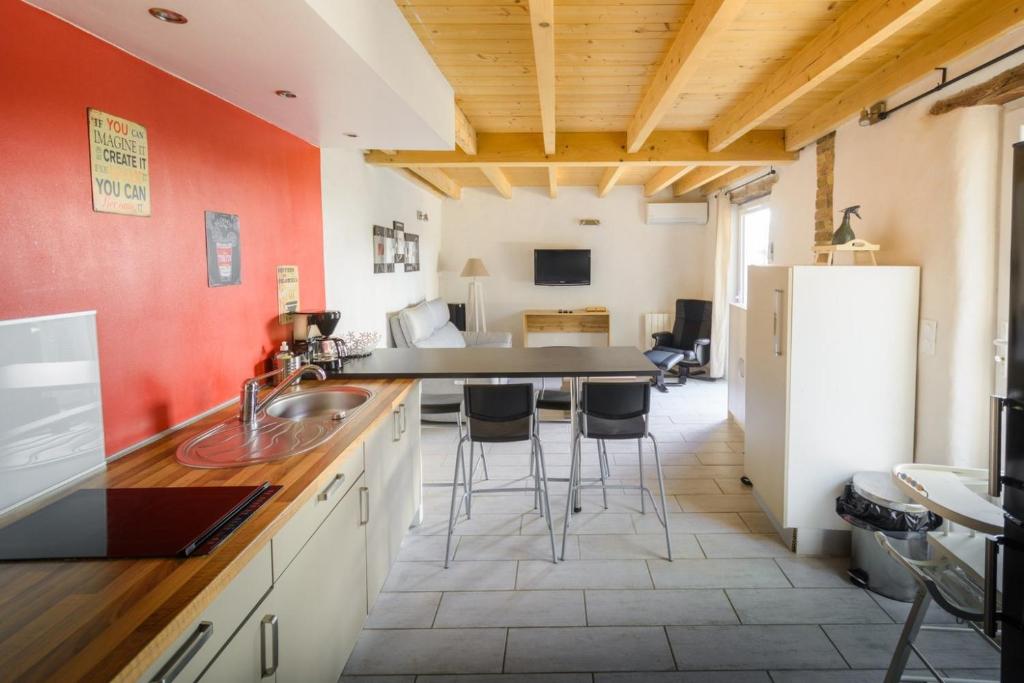 uma cozinha com paredes cor de laranja e uma mesa e cadeiras em Maisonnette Cosy à Proximité de la Gare em Valence
