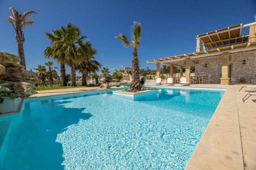 une piscine bordée de palmiers et une maison dans l'établissement Villa Ametista, à Taviano