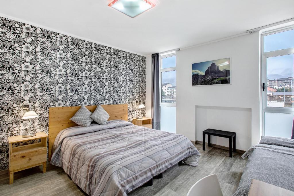 um quarto com uma cama e uma grande janela em Alpen Pila Residence Loft 1 em Aosta