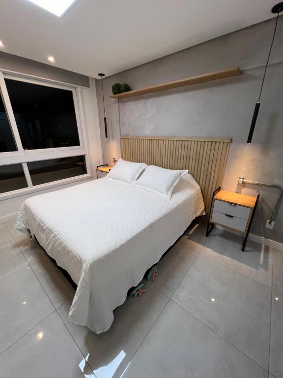 Un dormitorio con una gran cama blanca y una ventana en Apartamento/Studio Novo Hamburgo en Novo Hamburgo