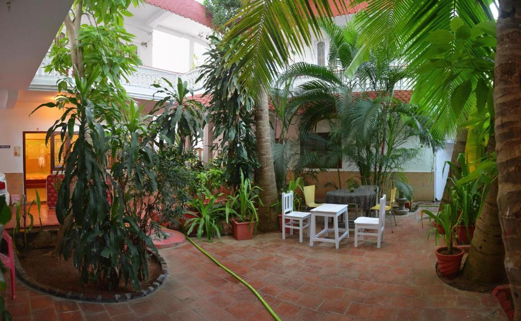 a courtyard with palm trees and a table and chairs at Daphne Hotel in Mahabalipuram