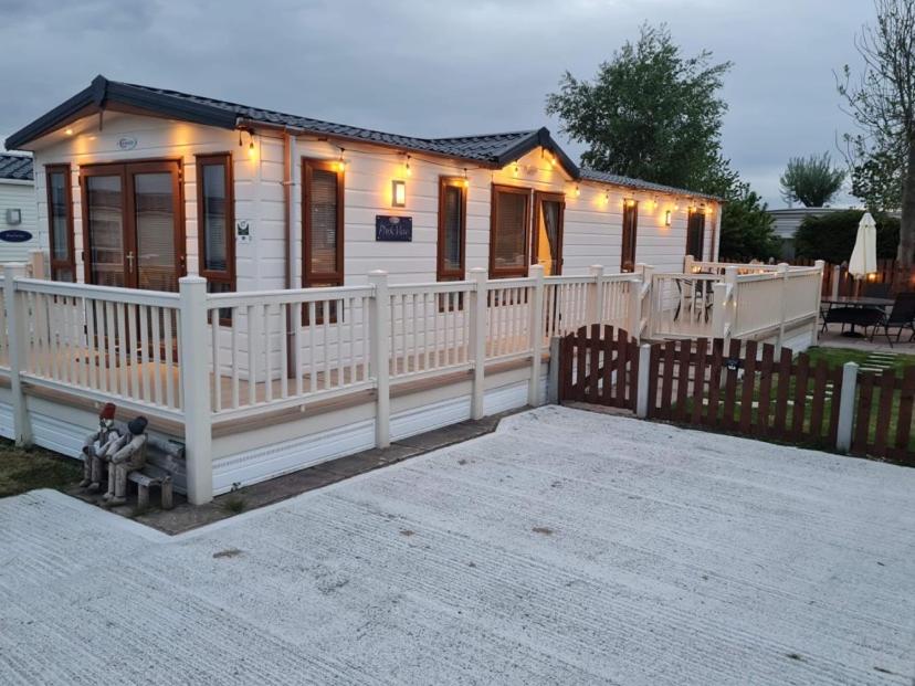una piccola casa bianca con una recinzione bianca di 2 Bed Lodge Style Caravan with Hot Tub & Private Garden at Patrington Haven Leisure Park a Patrington