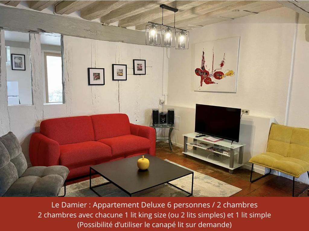 a living room with a red couch and a tv at Le Pigeonnier centre historique Auxerre in Auxerre