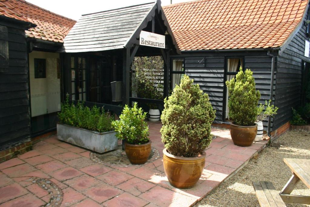 a house with three potted plants on a patio at Farmhouse Inn in Thaxted