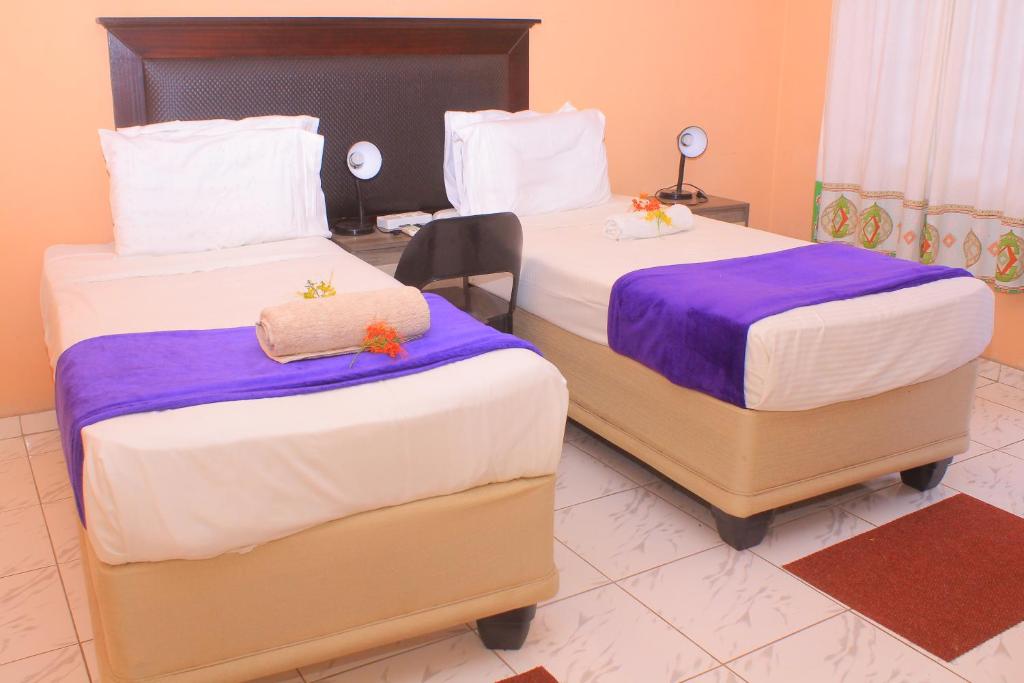 2 Betten mit lila und weißer Bettwäsche in einem Zimmer in der Unterkunft Luma Guest House in Kasane