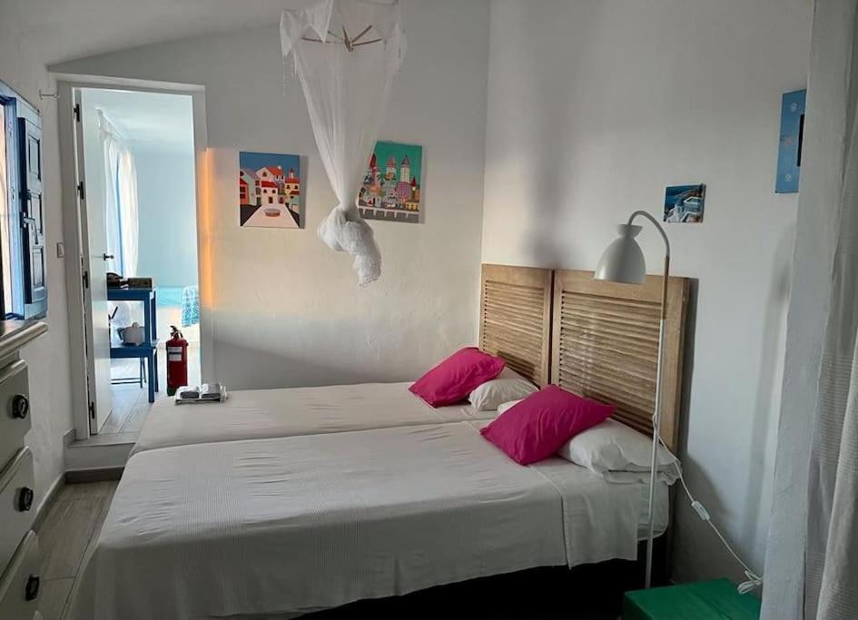 um quarto com 2 camas e almofadas cor-de-rosa em CASITA LINDA em Facinas