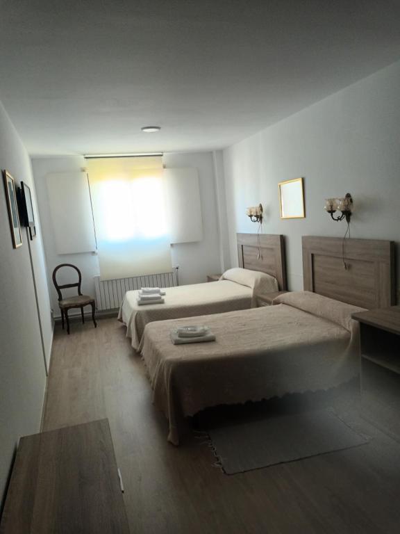 a bedroom with two beds and a chair and a window at Hostal padornelo in Mondoñedo