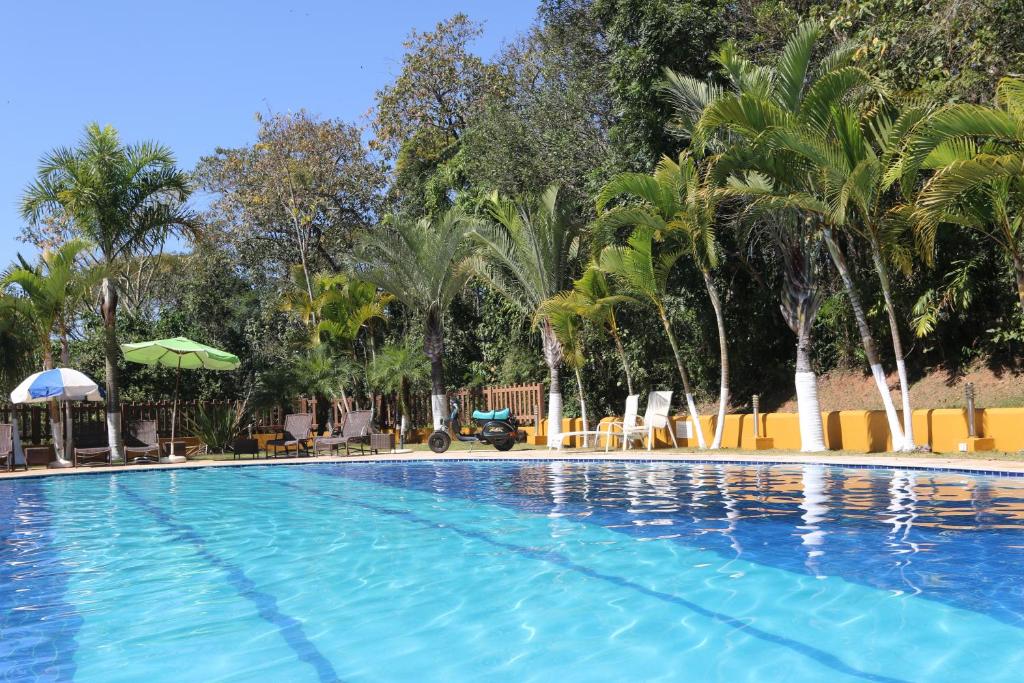 a large swimming pool with palm trees in a resort at Pousada Canto da Enseada in Nazaré Paulista