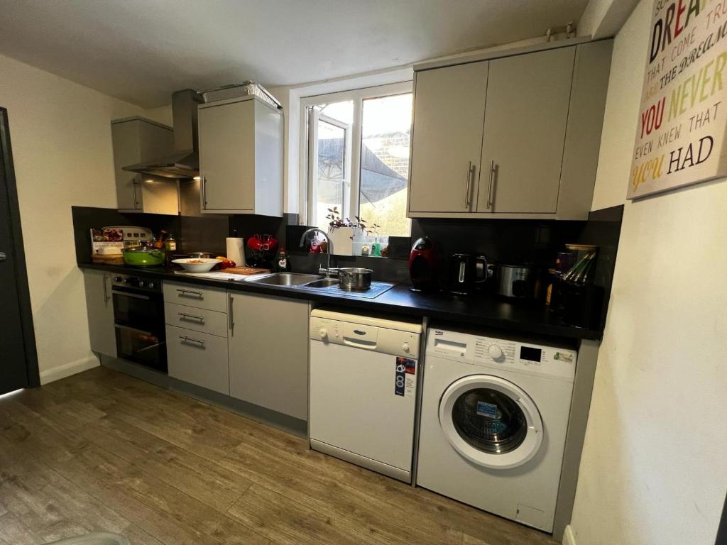 a kitchen with a washing machine and a washer at Lovely 2 bedroom holiday home with free parking in Plumstead
