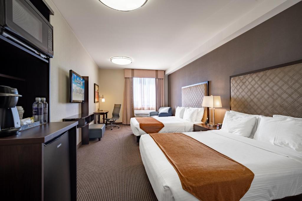 a hotel room with two beds and a desk at Acclaim Hotel by CLIQUE in Calgary
