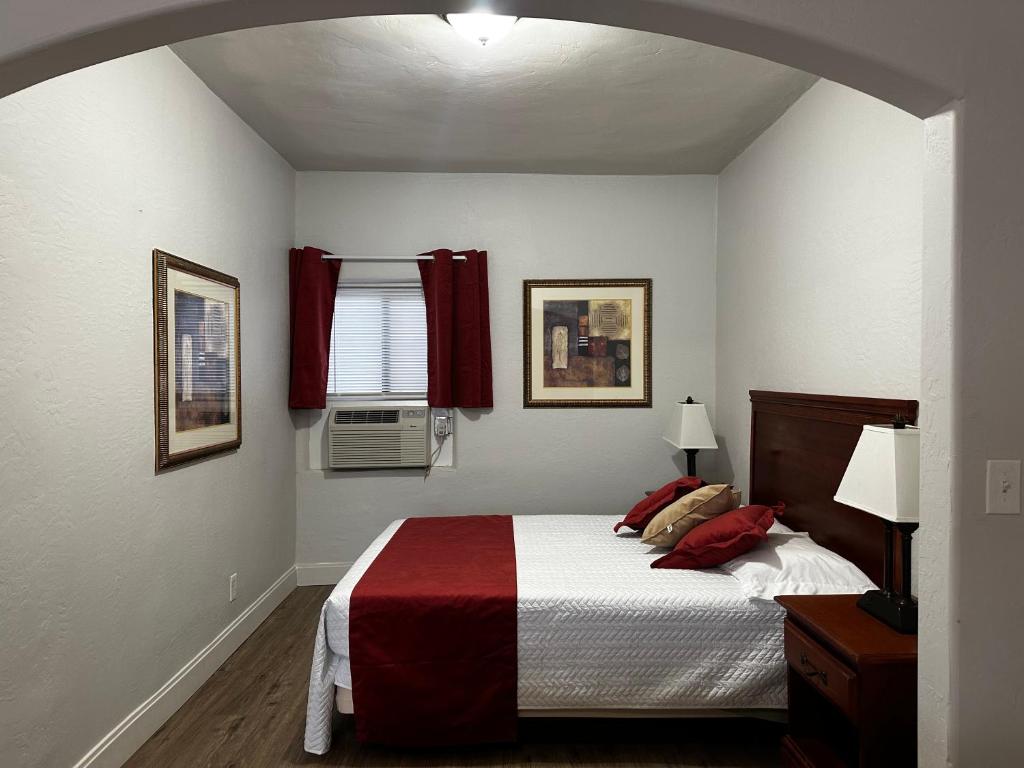 um quarto com uma cama com um cobertor vermelho e branco em Arizona 9 Motor Hotel em Williams