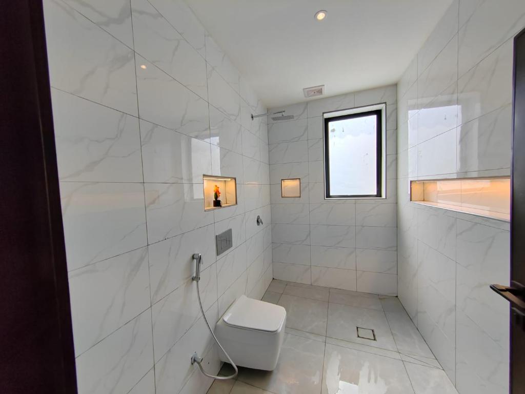 ein weißes Bad mit einem WC und einem Fenster in der Unterkunft شاليه ومنتجع ملك in Dschāzān