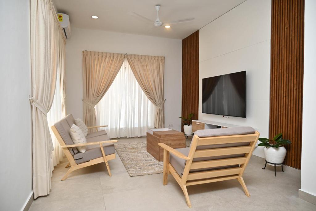 a living room with two chairs and a flat screen tv at The Chelsea TownHouse C in Accra