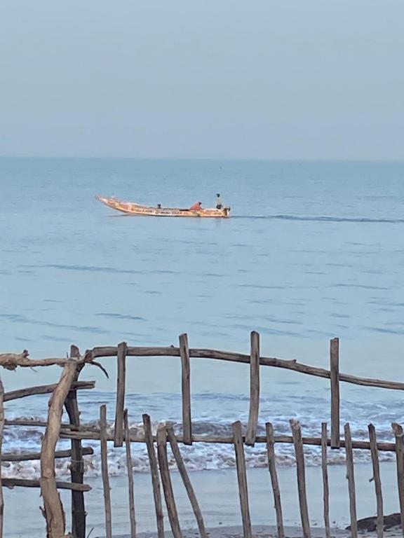 Chambre en bord de mer …(pied dans l’eau) في Ngalou Sessène: قارب في الماء بجانب سياج خشبي