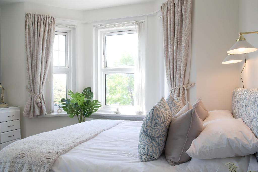 um quarto com uma cama com almofadas e janelas em Poole Park House em Poole