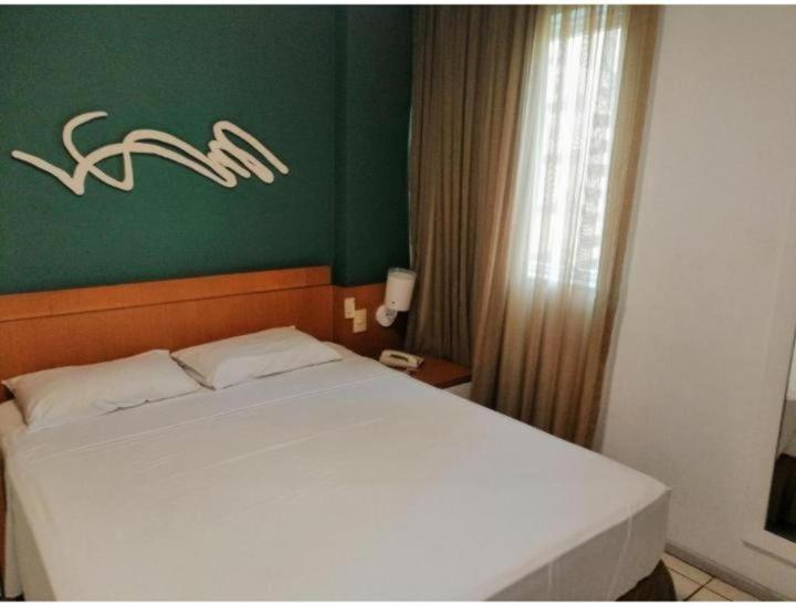 1 dormitorio con cama blanca y pared verde en Praia do Canto Apart Hotel - Bristol's, en Vitória