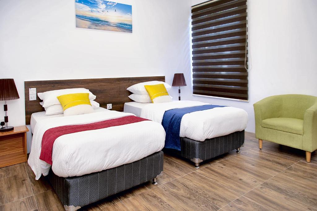 a hotel room with two beds and a chair at Manta Sky Inn in Dharavandhoo