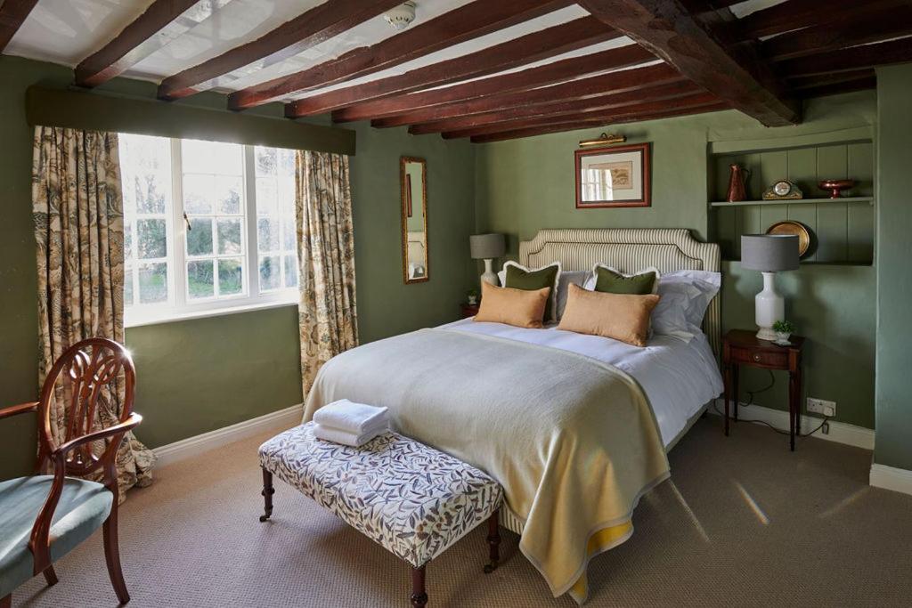 a green bedroom with a large bed and a chair at Martin Arms in Colston Bassett