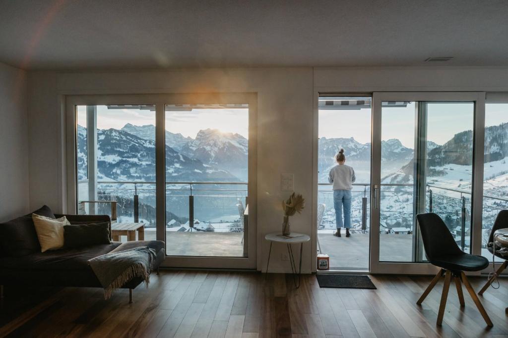 un hombre parado en un balcón con vistas a las montañas en Apartment Fortaleza, en Amden
