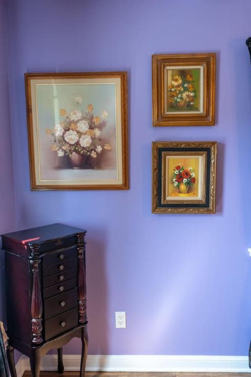 three pictures of flowers on a purple wall with a dresser at Cardinal Inn Romantic Room in Cornwall