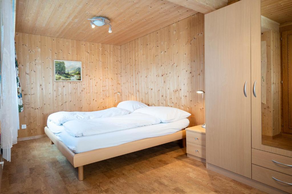 a bed in a room with a wooden wall at Chalet Chapfwald in Amden