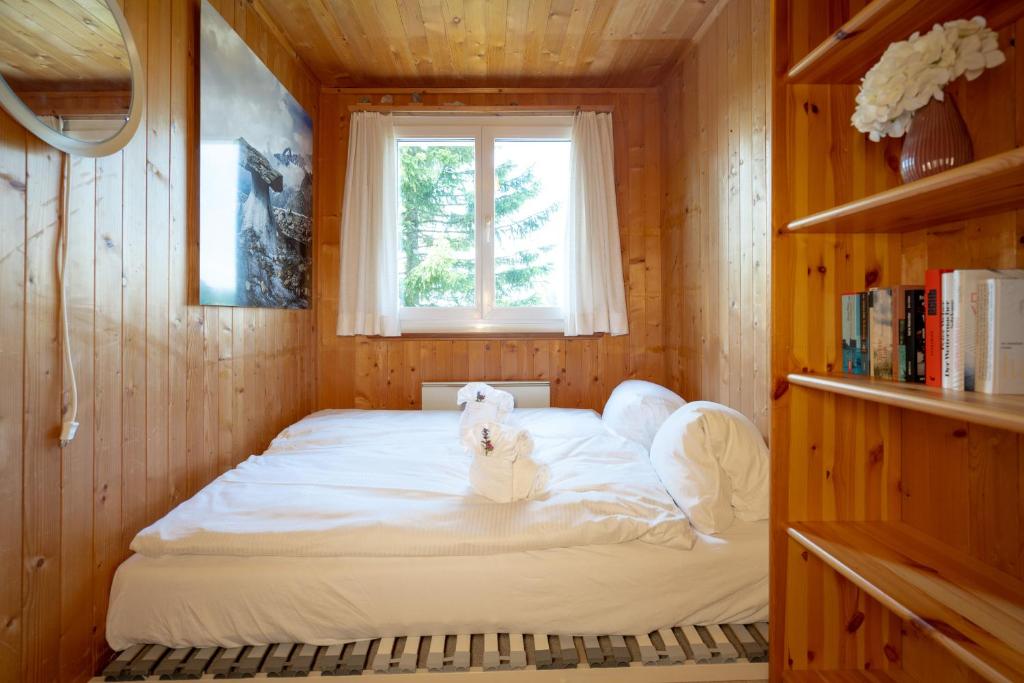 Bett in einem Holzzimmer mit Fenster in der Unterkunft Chalet Sönderli in Amden