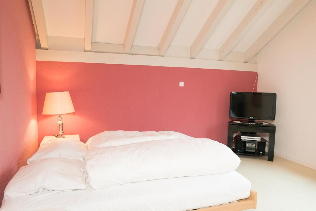 1 dormitorio con cama blanca y pared roja en Apartment Hinterberg, en Amden