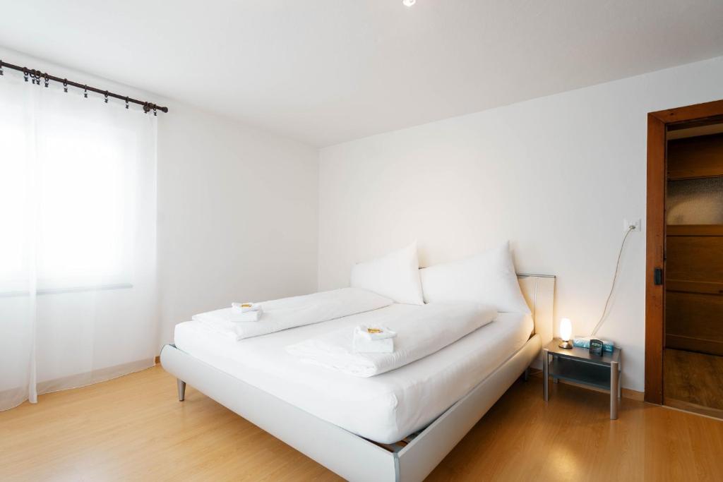 uma cama branca num quarto branco com uma mesa em Apartment Raingüetli em Amden