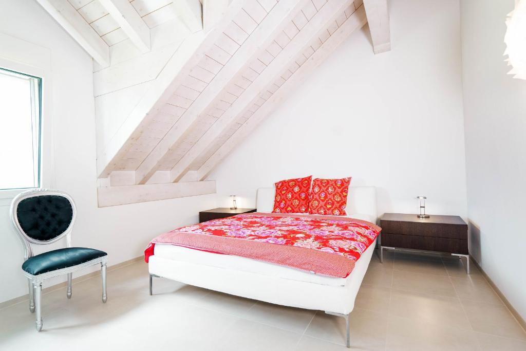 a white bedroom with a bed and a chair at Apartment Soldanella in Amden