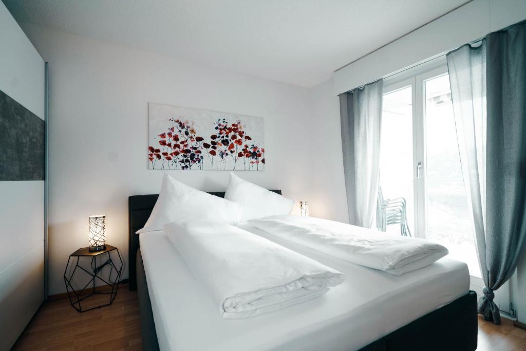 a white bed in a room with a window at Apartment Panoramablick in Amden