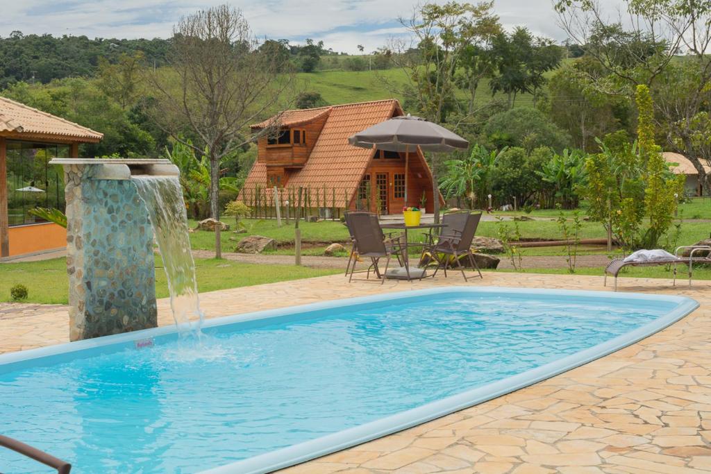 a swimming pool with a fountain in a yard at Aconchego da bocaina in Cunha