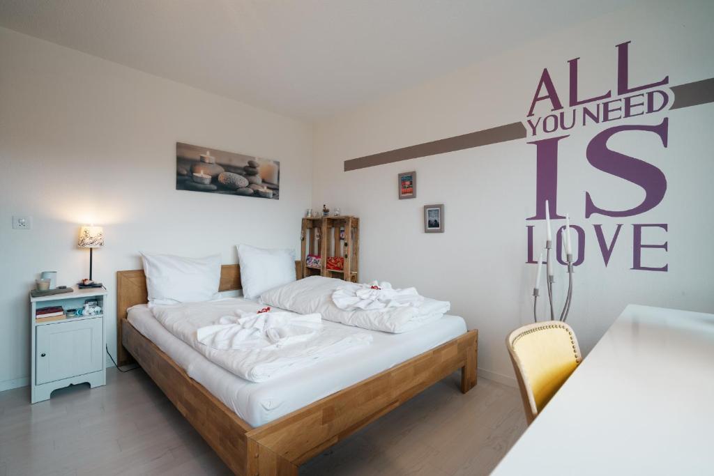 a bedroom with a bed and a sign that says all you need is love at Apartment Mattstogg mit Charme in Amden