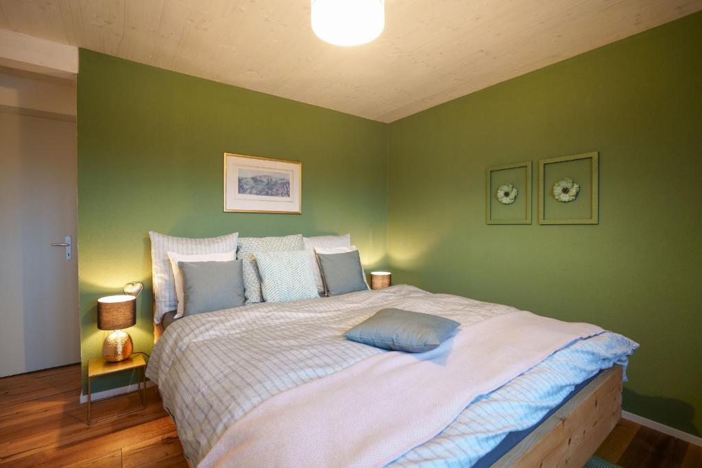 um quarto com uma cama grande e paredes verdes em Chalet Fridolin em Amden