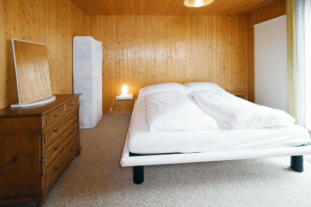 a bedroom with a white bed and a wooden wall at Apartment im Chalet Biodola in Amden