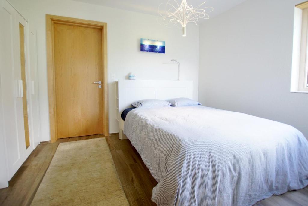 アムデンにあるBijou am Bachの白いベッドと木製のドアが備わるベッドルーム1室が備わります。