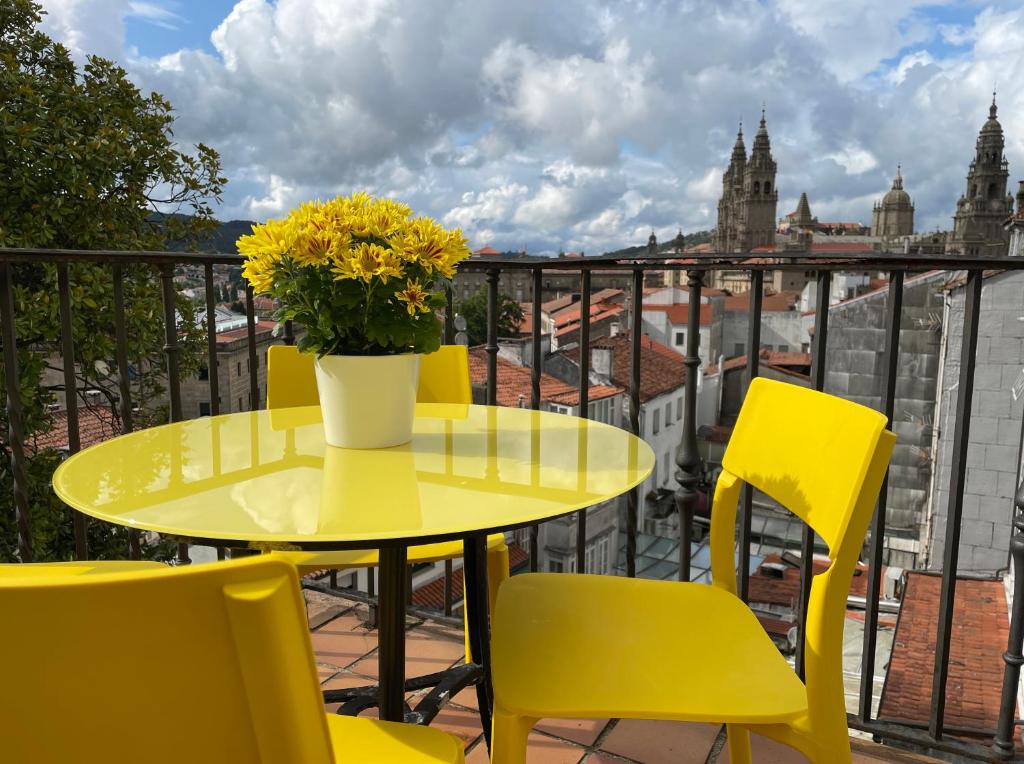 una mesa amarilla y sillas con un jarrón de flores en el balcón en Yellow Home, en Santiago de Compostela
