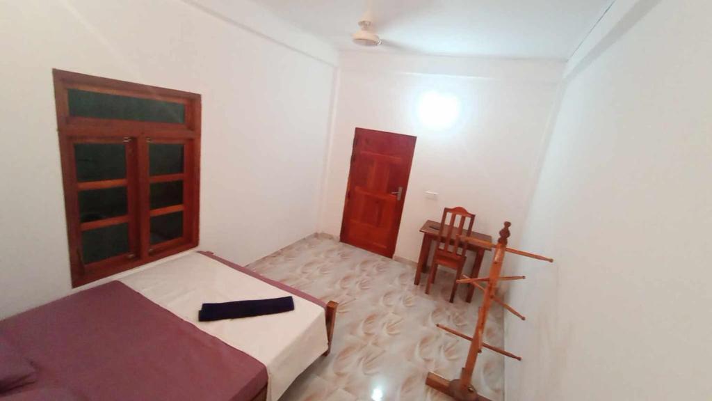 een kleine kamer met een bed en een houten deur bij 'Villa'chava in Chavakachcheri